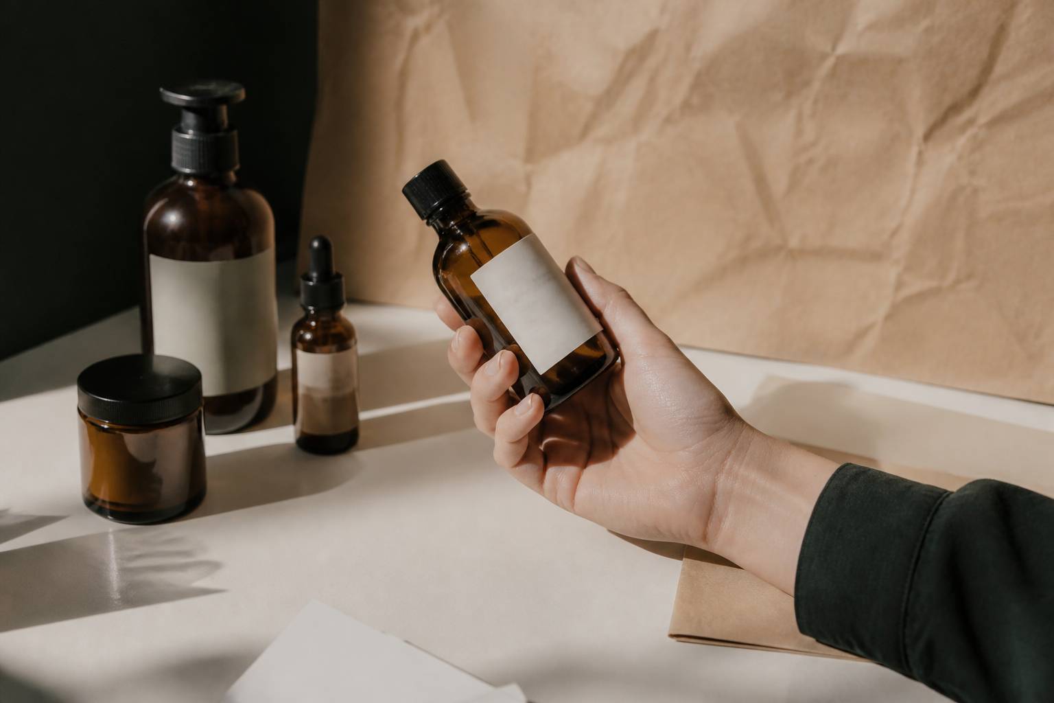 Main retournant un flacon de cosmétique pour lire sa composition, étiquette floutée sans texte